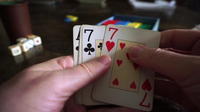 Player's hands revealing a full house poker combination of three aces and two sevens during a game