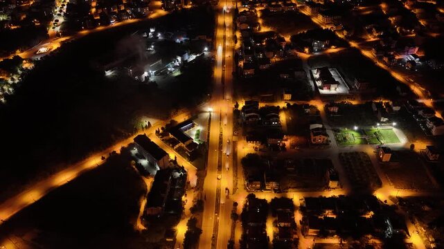 A mesmerizing bird's-eye view of a city street sparkling with nighttime lights. An aesthetically pleasing drone shot capturing the interplay of vehicle traffic and streetlights.