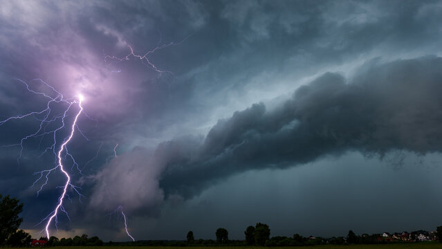 Spectacular forked lightning strike illuminating dramatic storm clouds at night. Close-up of powerful electrical discharge