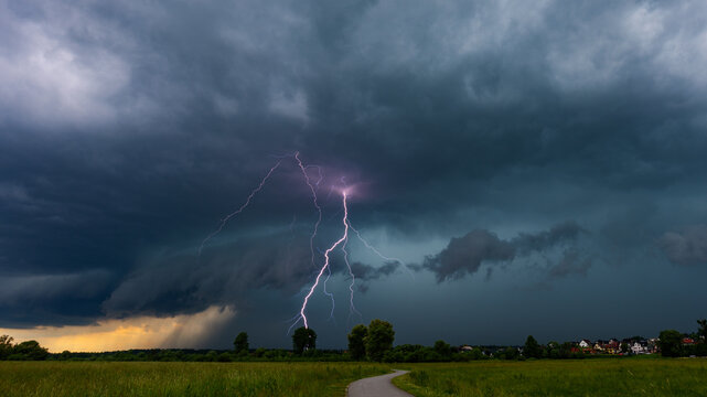 Dramatic lightning bolt striking from a powerful shelf cloud during severe summer thunderstorm. Extreme weather landscape