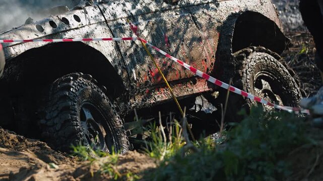 Intense close up of powerful 4x4 truck stuck in deep mud. Spinning tires splash dirt during extreme offroad competition. Dynamic action shot of rugged motorsport challenge in dirty terrain