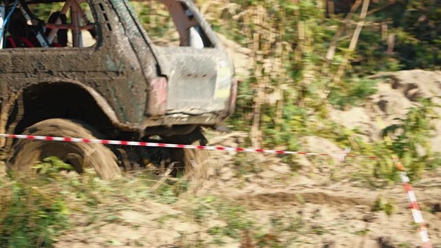 The dirty tires of an SUV drive through sand. The panoramic shot conveys the speed and power of extreme motorsport on a dirt track. Rough, dirty, and powerful