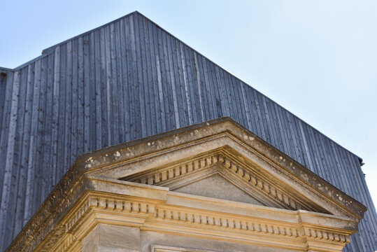 Juxtaposition of Old Stone Monument and Modern Wooden Building at Montmartre Cemetery in Paris, France