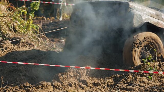 Powerful 4x4 vehicle battles extreme terrain. Smoke billows from engine as wheel spins, splashing mud during intense offroad motorsport rally. Winch cable assists recovery from deep dirt