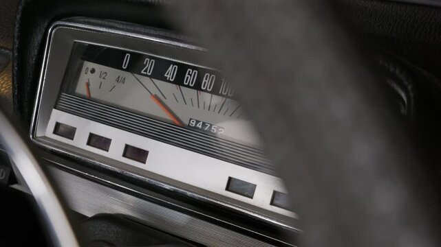 A close-up view of a classic car dashboard features an analog speedometer with orange needles and Cyrillic text. Concept of vintage technology, automotive history, and road travel nostalgia.