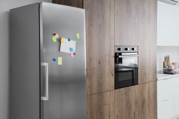 Modern kitchen interior with stainless steel refrigerator built-in oven and wooden cabinets...