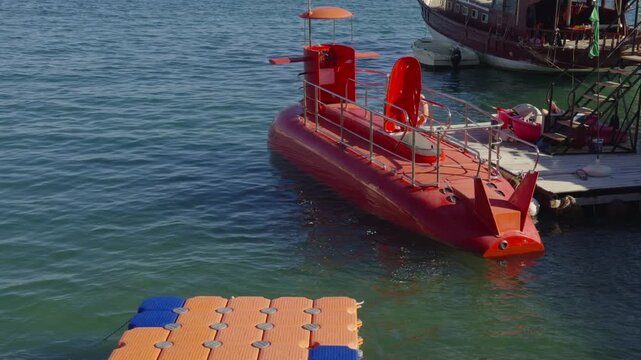 Red Semi Submarine Tourist Boat Docked Near Wooden Pier. Excursion Watercraft Vessel For Underwater Viewing Marine Life Activity