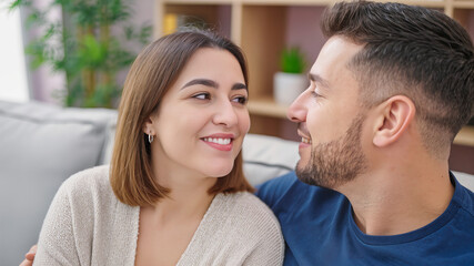 Fototapeta premium Close up of a happy looking lovingly at each other while relaxing on a comfortable gray sofa in a modern living room