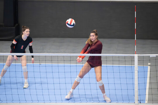 College volleyball players passing the ball in an indoor sixes game