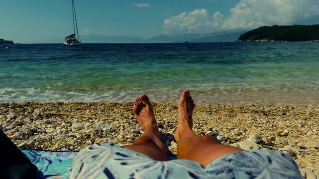 Traveler Relaxing On Pebble Beach Looking At Turquoise Sea Water Surface. Summer Vacation