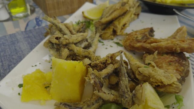 Crispy Deep Fried Small Anchovy Fish With Fresh Lemon Slice And Polenta. Mediterranean Seafood Appetizer Dish