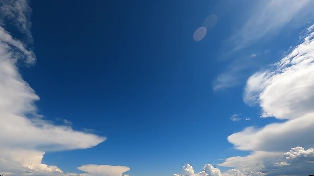 Wide angle background of deep blue sky framed by white wispy clouds with subtle sun lens flare for sky replacement and outdoor environmental design templates