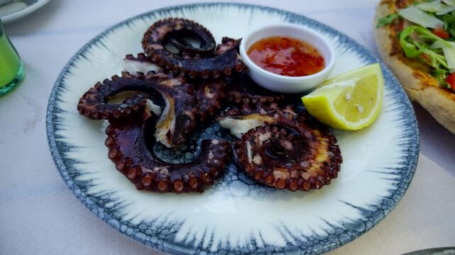 Grilled Octopus Tentacles With Lemon Slices And Sweet Chili Sauce Bowl. Mediterranean Seafood Dish