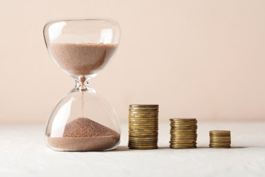 Hourglass and decreasing coin stacks financial decline, time management, and investment risk