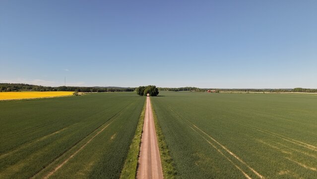 Aerial view of the straight road leading towards Bj&auml;rka-S&auml;by New Castle (Nya Slottet) in Sweden. Cinematic drone perspective of a rural road and historic European architecture.