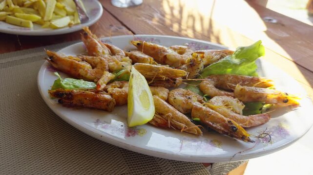Fried King Shrimps On Plate With Fresh Lemon Slice And Green Salad Leaves. Grilled Prawns Appetizer Dish. Mediterranean Seafood Culinary