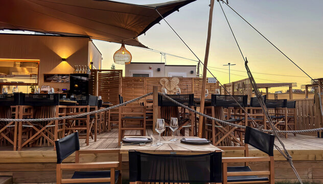 Elegant Outdoor Restaurant Terrace at Sunset with Wooden Tables and Warm Lighting