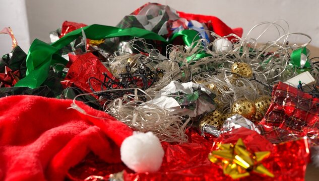 Christmas wrapping paper waste. Broken Christmas tree lights, old decorations, holiday cards, tin foil, festive plastic packaging, ribbons