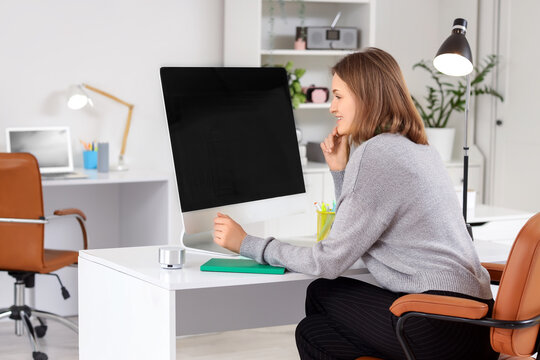 Happy female programmer with computer working in office