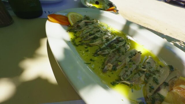 Marinated Anchovies Fillet In Olive Oil With Herbs And Lemon Slices. Mediterranean Seafood Appetizer Dish