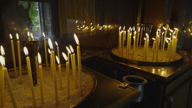Burning Wax Candles In Sand Inside Orthodox Church Interior. Christian Religious Ritual. Warm Candlelight Flame In Holy Temple