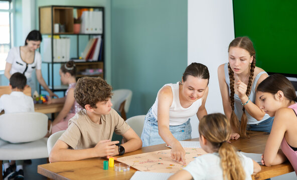 Group of teens playing board game. Teenagers have fun during meetings and gatherings, enthusiastically and excitedly fulfill conditions of game