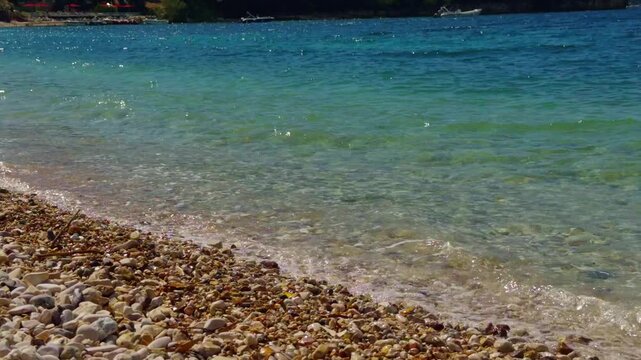 Clear Turquoise Sea Waves Crashing On Pebble Beach Shore Line.  Coastal Landscape On Sunny Summer Day
