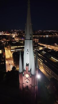 Aerial view of Saint Clara Church (Klara kyrka) in Norrmalm, downtown Stockholm, Sweden. Cinematic drone shot of the iconic Gothic Revival brick tower and cityscape.