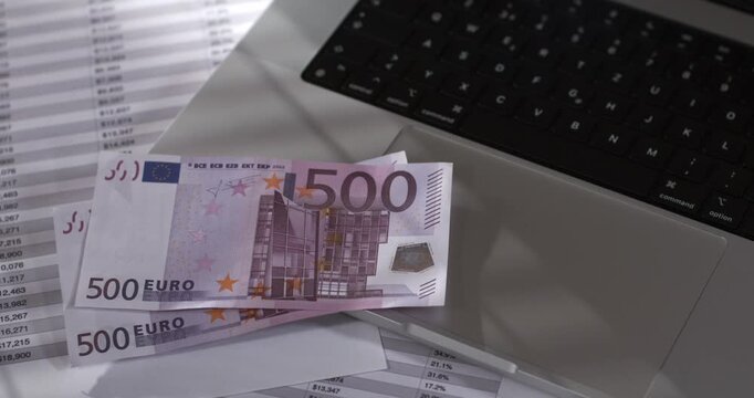 Close-up view of euro bills near a laptop and papers