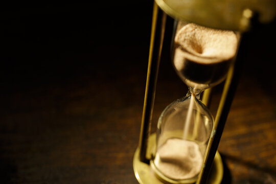 Antique hourglass in a dark room. Vintage atmosphere of antiquity.