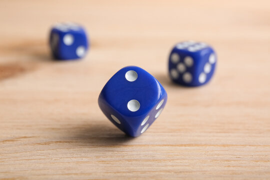 Blue game dices on wooden background, closeup