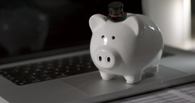 Piggy bank on laptop keyboard with black background and soft lighting