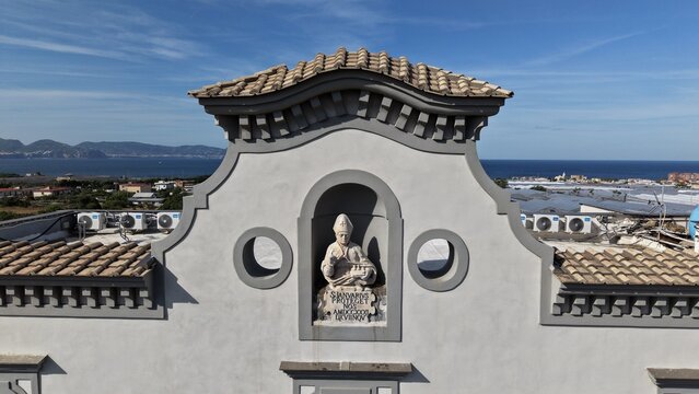 Aerial drone view of historic villa facade with stone statue niche in Torre del Greco with sea and islands in background, Naples, Italy
