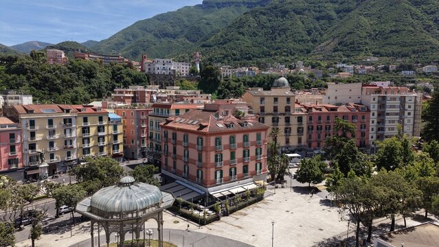 Aerial drone view of Castellammare di Stabia town square with Cassa Armonica gazebo, colorful buildings and green mountains, Naples, Italy
