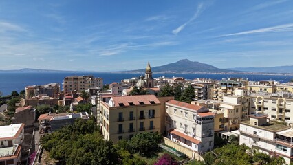Fototapeta premium Aerial drone view of Vico Equense rooftops with church bell tower and Mount Vesuvius volcano across the Gulf of Naples, Italy 