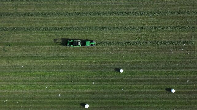 Tractor driving across a large field in rural nature seen from above