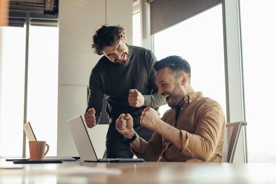 Joyful Caucasian Men Celebrating Achievement Together In Modern Office Environment, Engaging In Teamwork And Collaboration, Smiling And Supporting Each Other In Success.