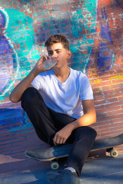 Young skateboarder drinking water from a bottle while taking a break