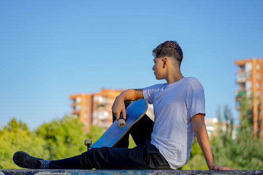 Young Man with a Skateboard Contemplating the Urban Outdoor Setting
