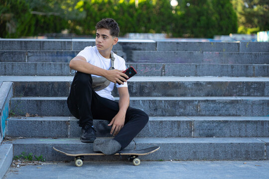 Young Person with a Skateboard and Cell Phone on an Urban Staircase