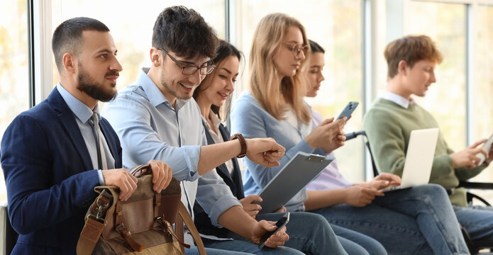 Young job applicants with man in wheelchair waiting for interview at office