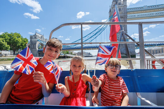 Children waving Union Jack flags on boat by Tower Bridge London