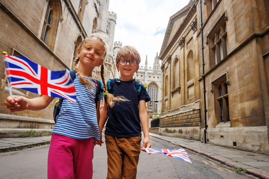 Two children tourists hold British flags on historic city street