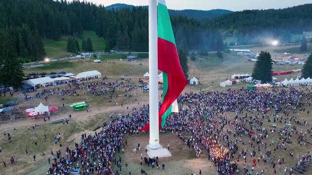Drone View of Raising the largest and tallest Bulgarian flag on the highest pole on Rozhen Peak in the Rhodope Mountains, near Pamporovo resort, Bulgaria.