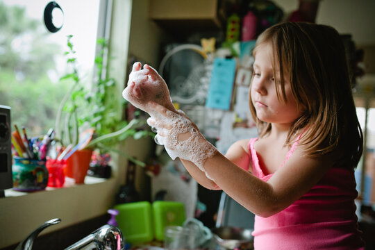 girl washing hands at kitchen sink