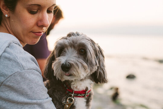 Woman holding her dog by a lake