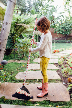 girl sweeping in yard