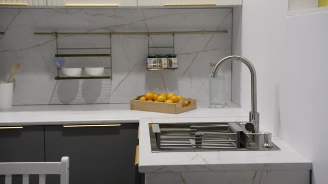 Video shows progressive reveal of a stylish modern kitchen with mint green cabinets, marble backsplash, black metal organizers. Smooth camera movement highlights design details functional layout