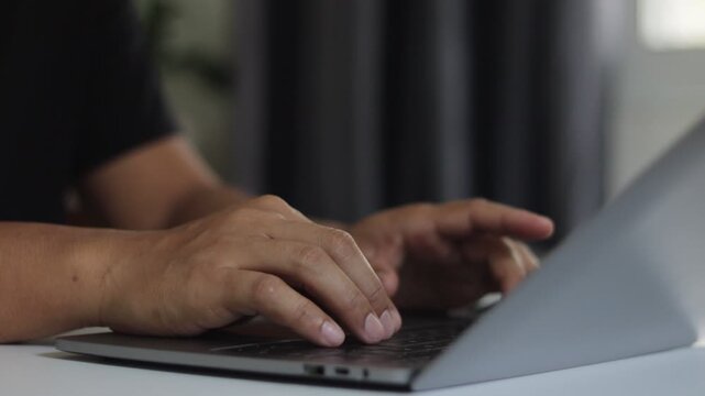 Closeup hand is typing on a laptop computer keyboard at home or in the office. Man working, learning, live chatting, browsing internet, using social networking, online remote support service customer.