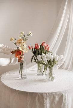Woman Hand Arranging Poppy Vase with Tulips on White Table